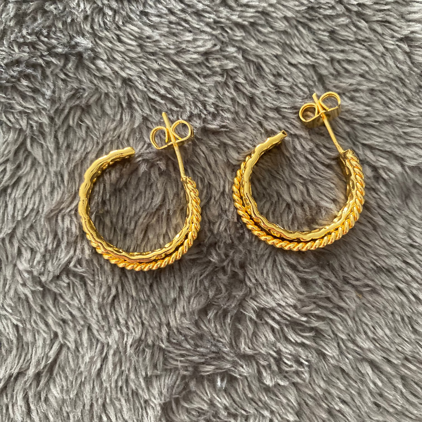 Gold hoop earrings on a gray fluffy surface